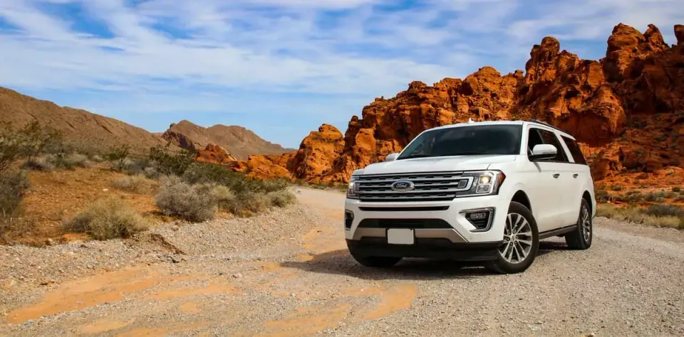 SUV auf einer Wüstenstraße zwischen den roten Felsen des amerikanischen Südwestens
