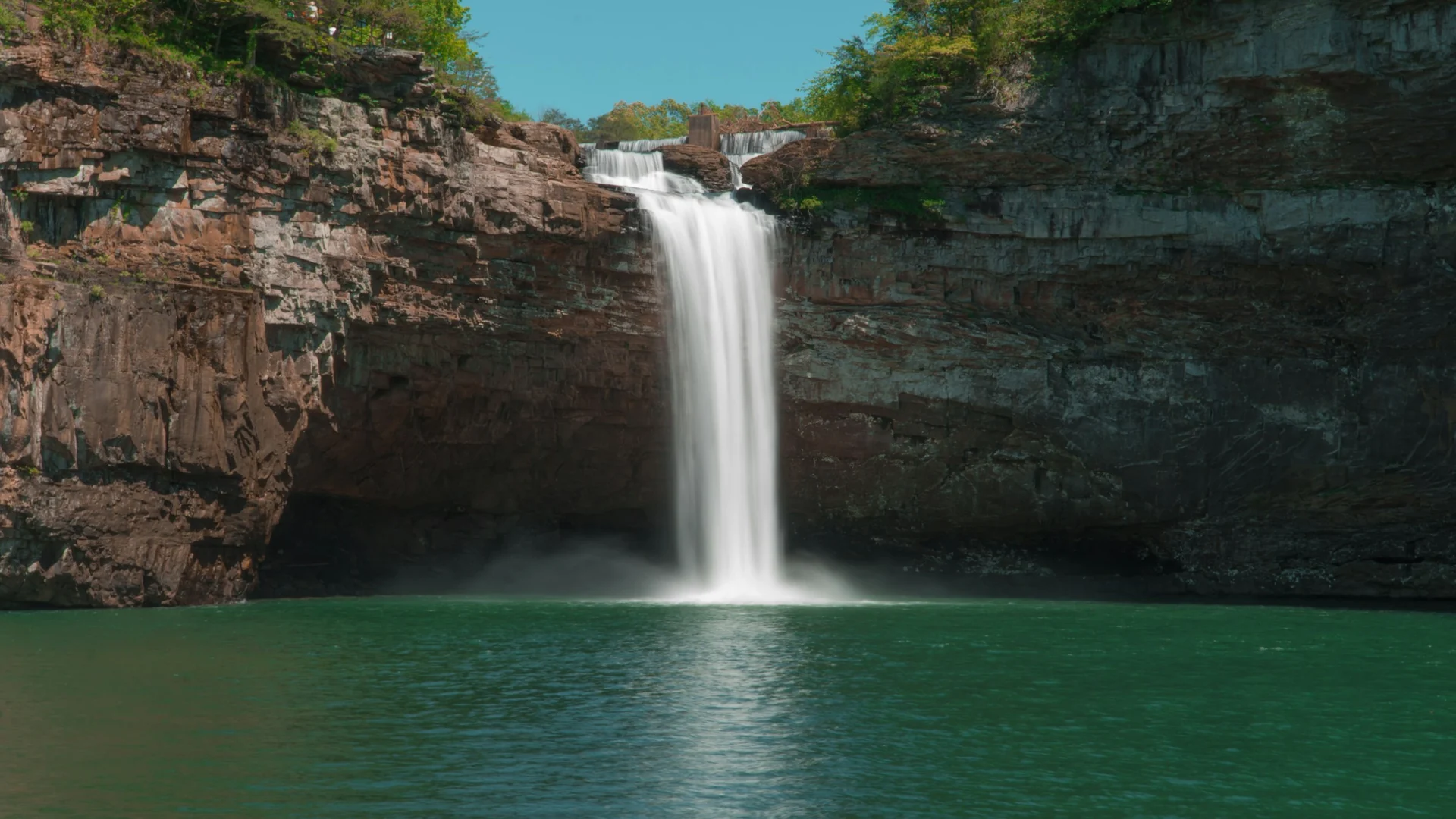 DeSoto Falls stürzt über eine rötliche Felswand in ein ruhiges, grünes Becken