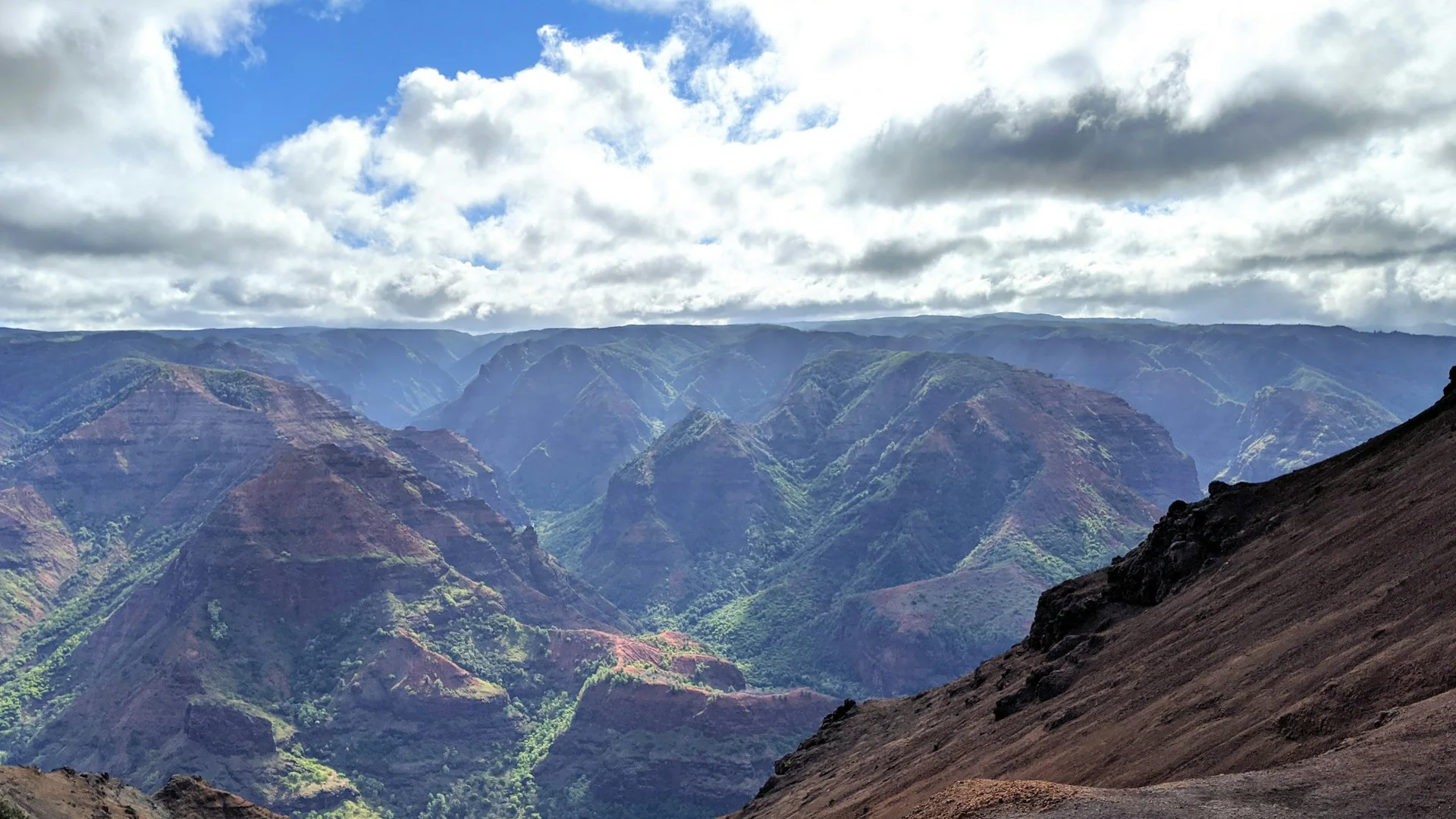 Tiefe grüne und rötliche Schluchten im Waimea Canyon auf Kauaʻi