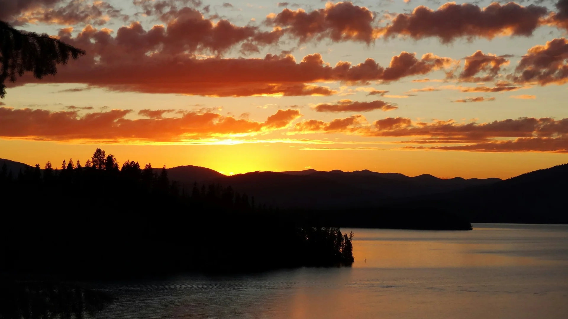 Rotes Abendlicht spiegelt sich im Priest Lake vor dunklen Bergsilhouetten