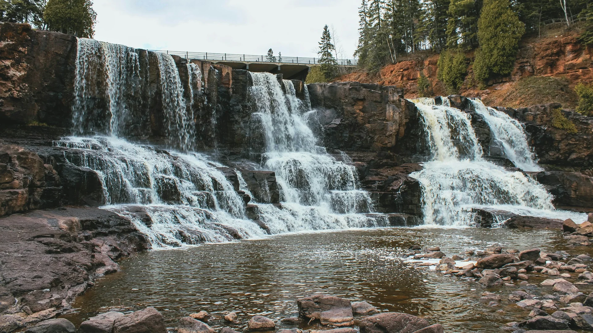 Breite Kaskaden der Gooseberry Falls zwischen Felsen und Wald in Minnesota