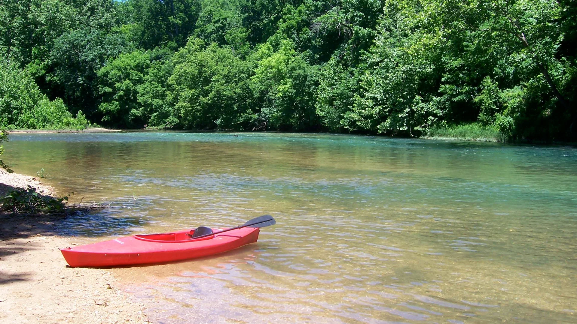 Rotes Kanu auf einer Kiesbank am klaren Current River in den Ozark National Scenic Riverways