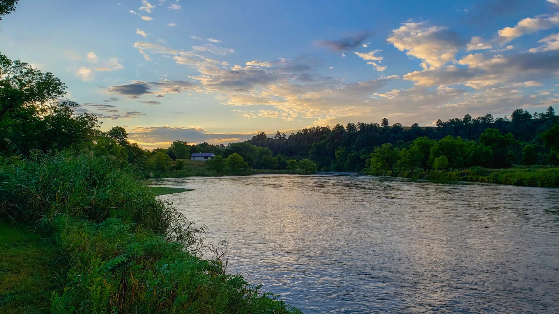 Breiter Niobrara River zwischen grünen Ufern bei warmem Abendlicht