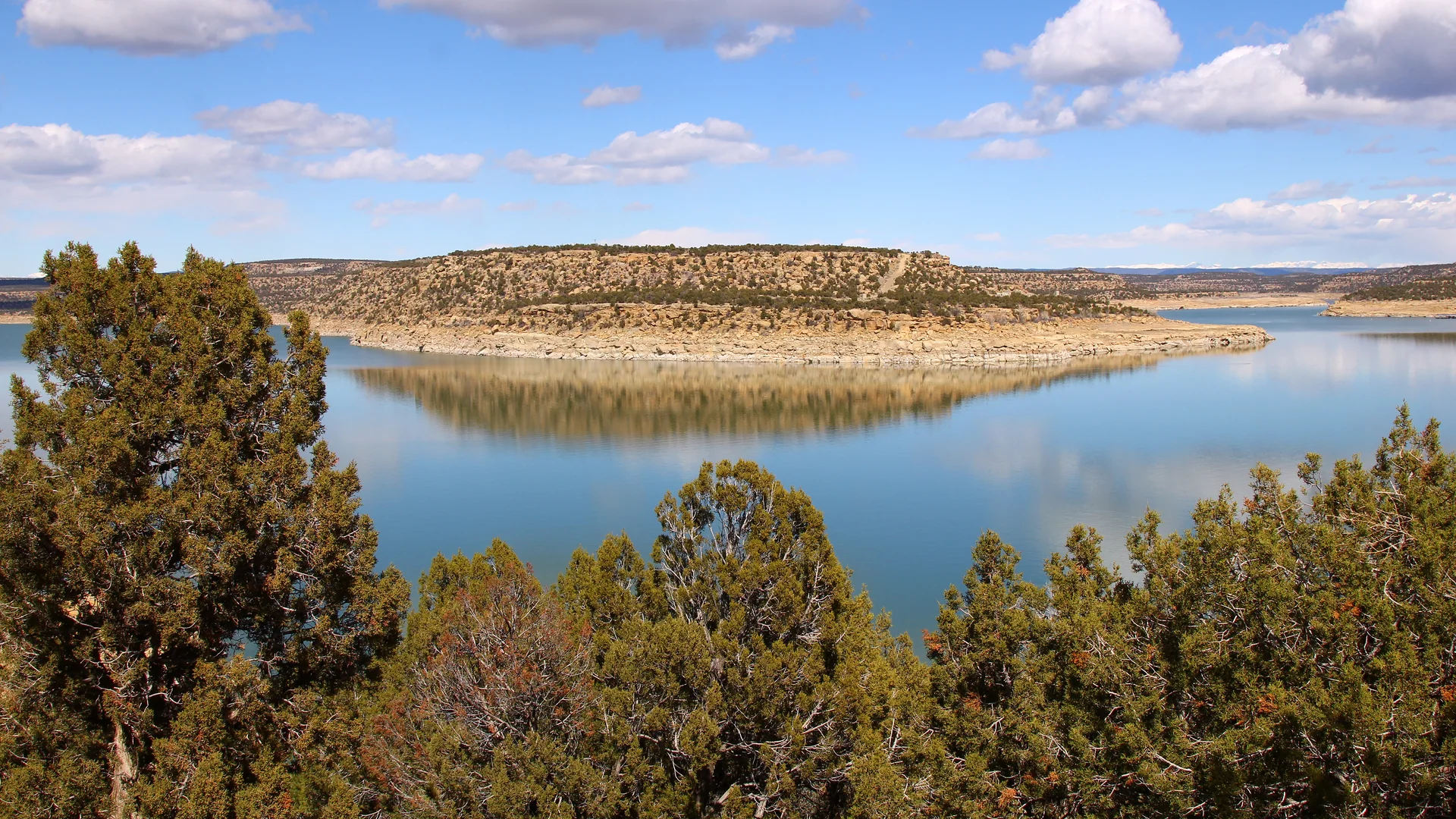 Blick über das blaue Wasser und die felsigen Ufer des Navajo Lake State Park