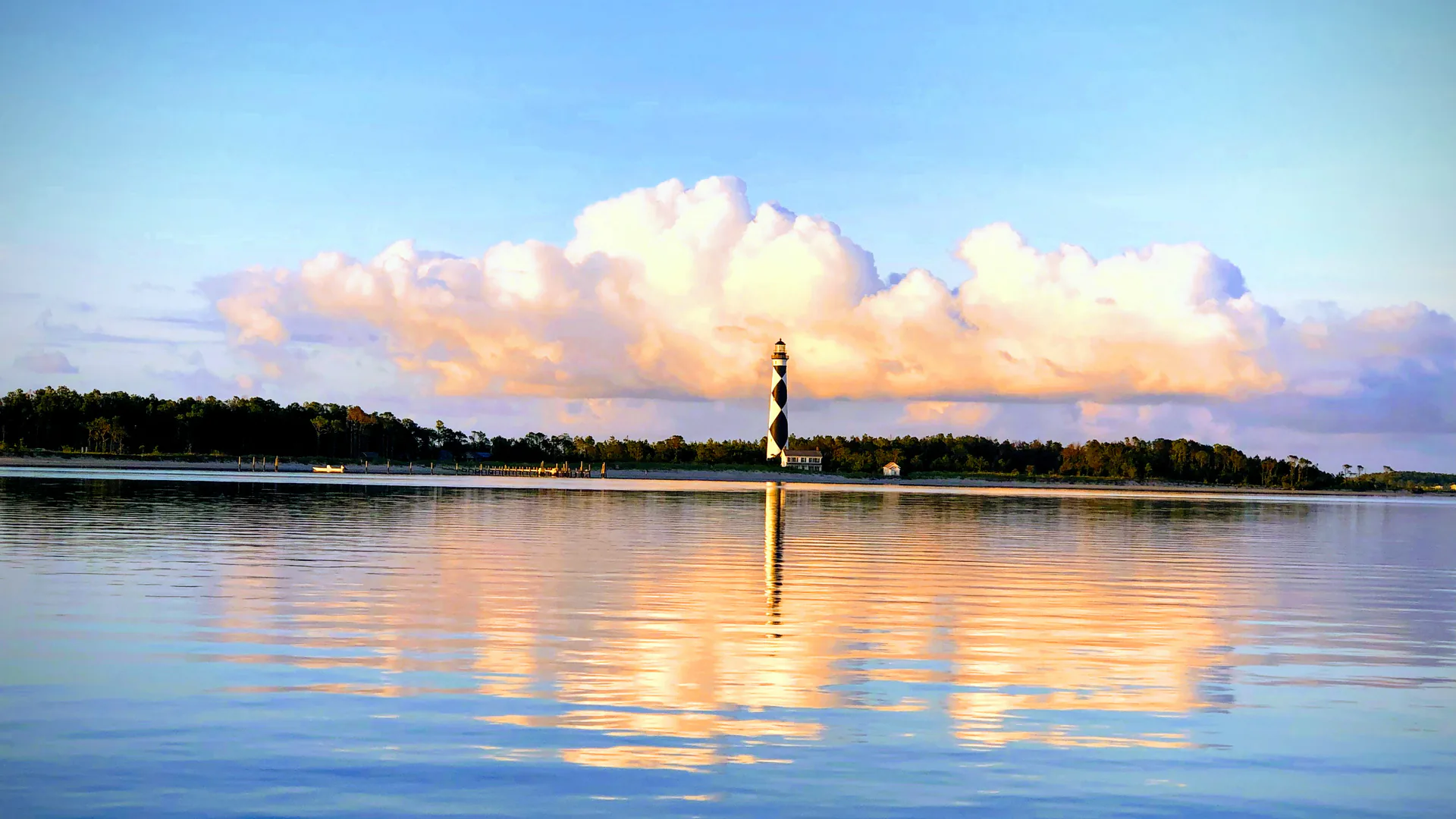 Cape Lookout Lighthouse spiegelt sich bei Sonnenaufgang im ruhigen Wasser vor der National Seashore