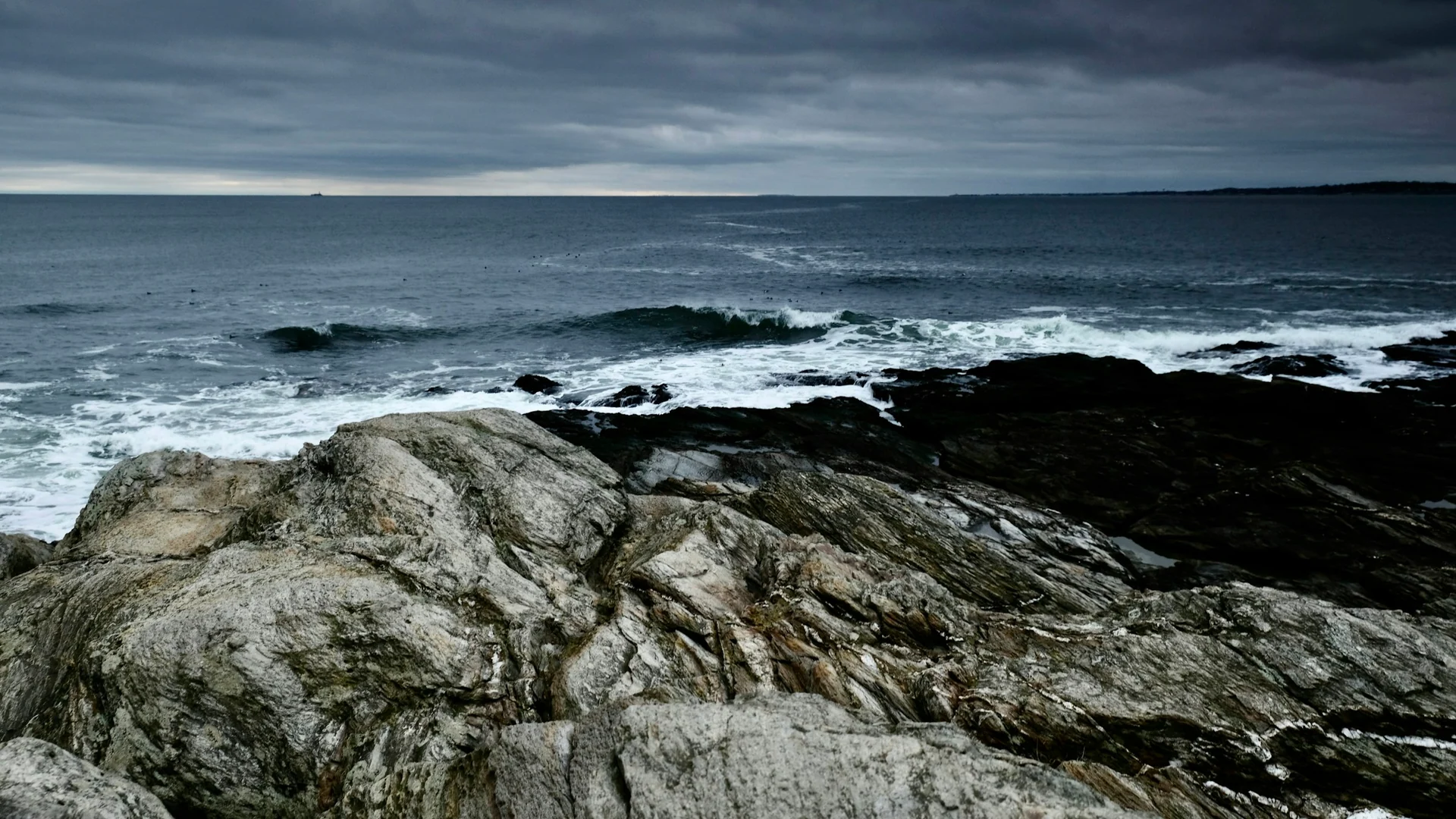 Dunkle Felsen und Atlantikbrandung im Beavertail State Park auf Jamestown