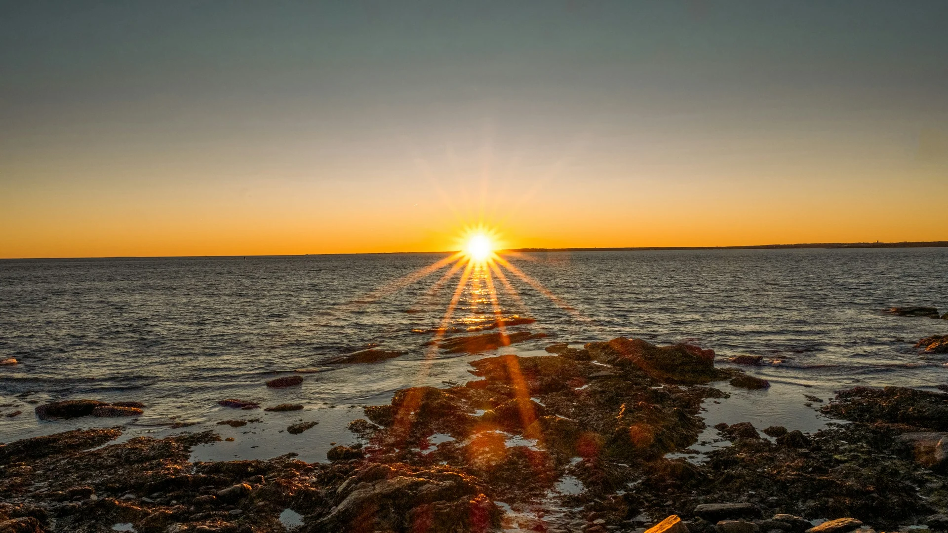 Tiefer Sonnenuntergang über Felsen und Atlantik im Brenton Point State Park