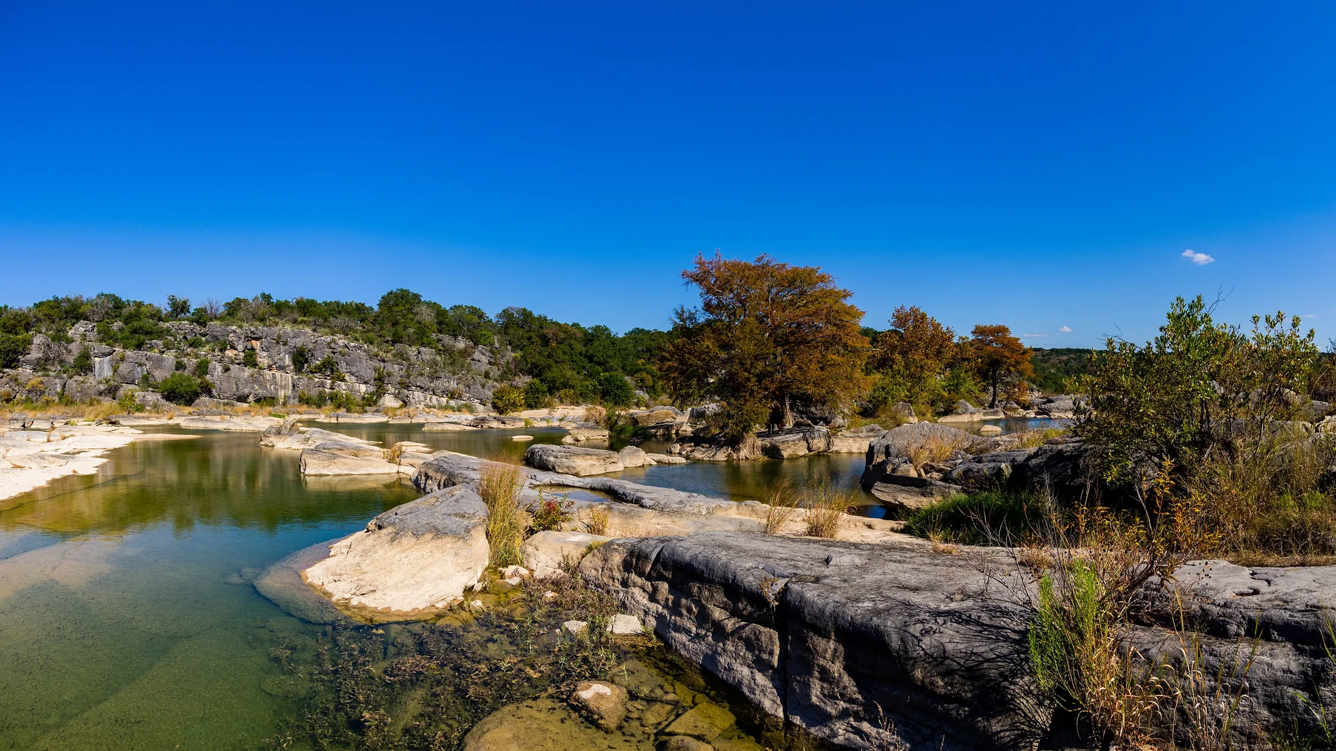 Heller Kalkstein, klares Wasser und herbstliche Bäume im Pedernales Falls State Park