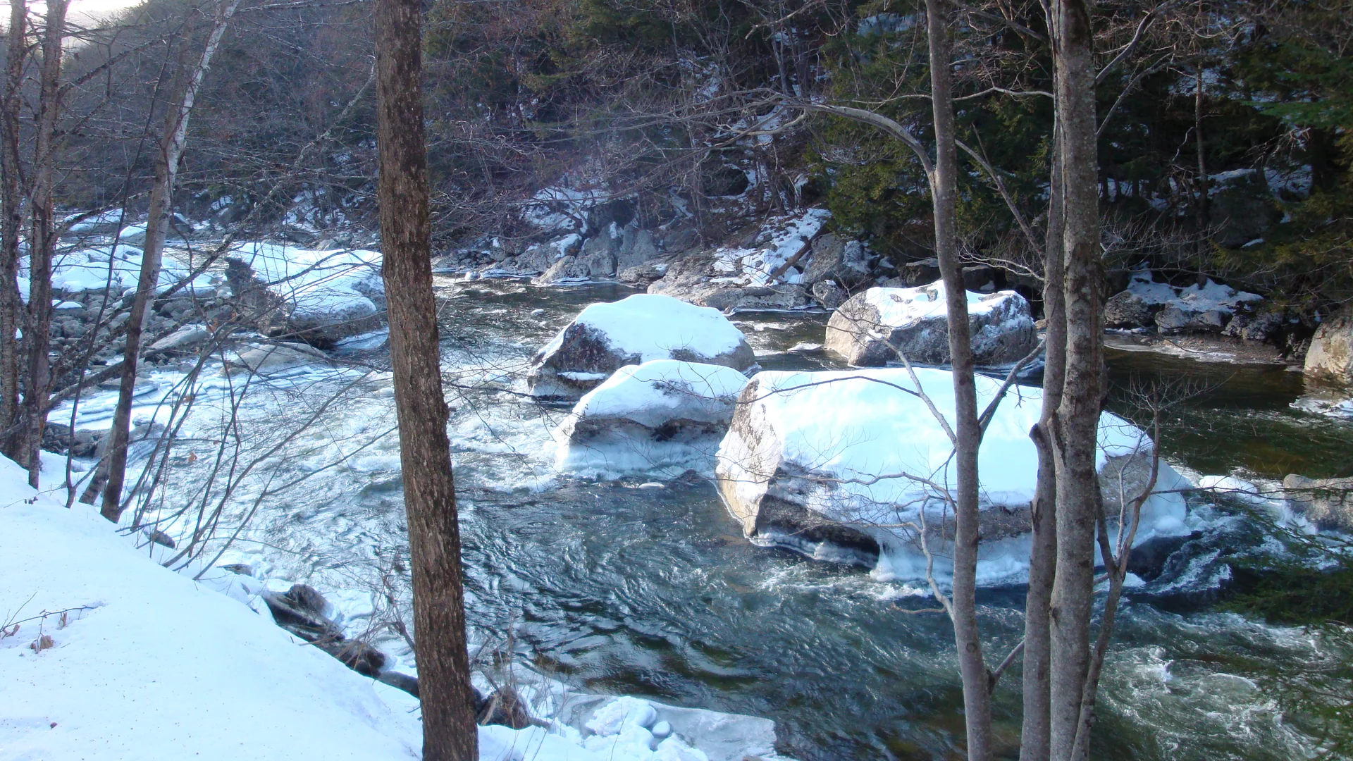 Verschneite Felsen und fließender West River im Jamaica State Park