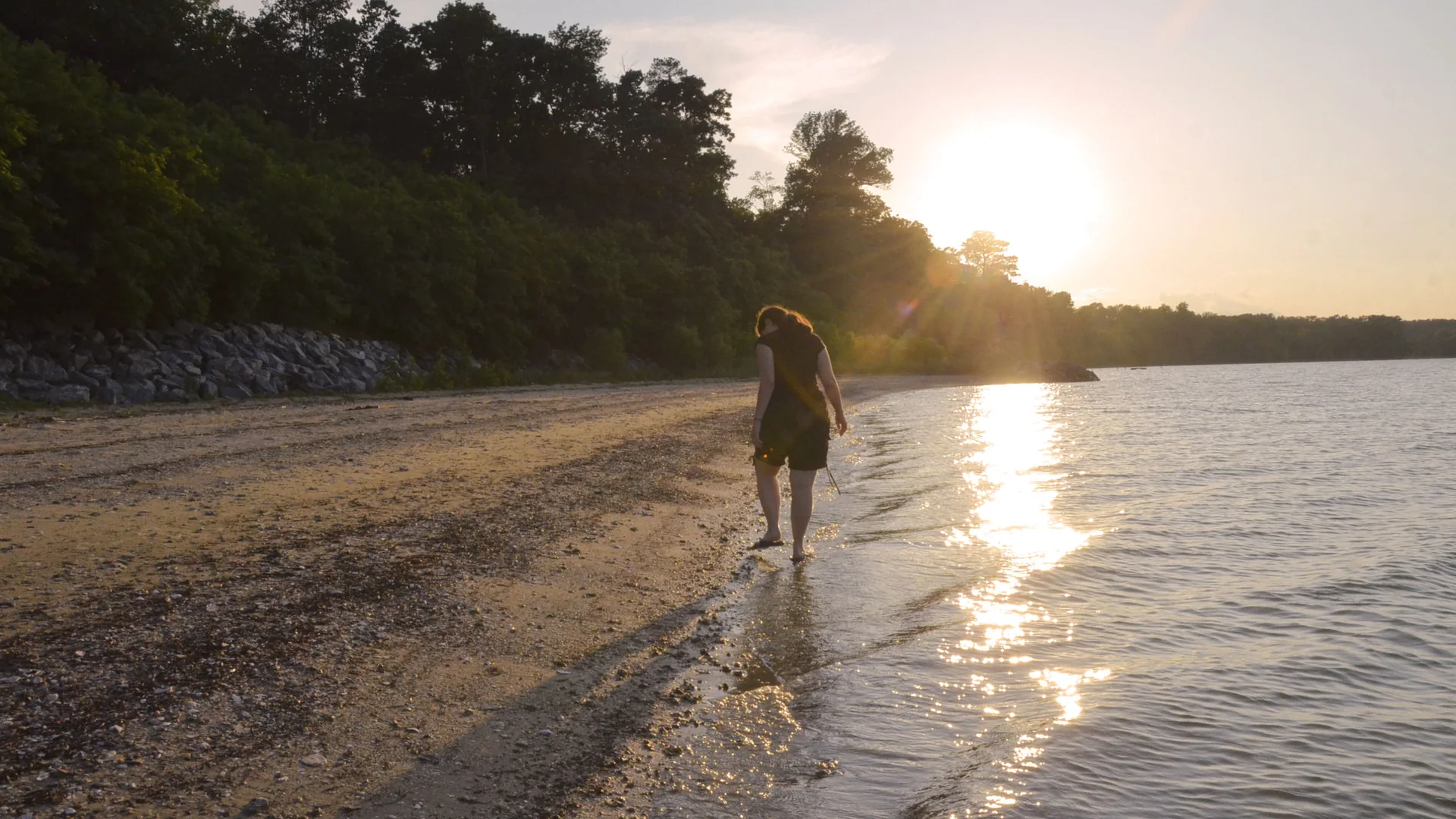 Besucherin am Ufer des James River im Chippokes State Park bei Sonnenuntergang