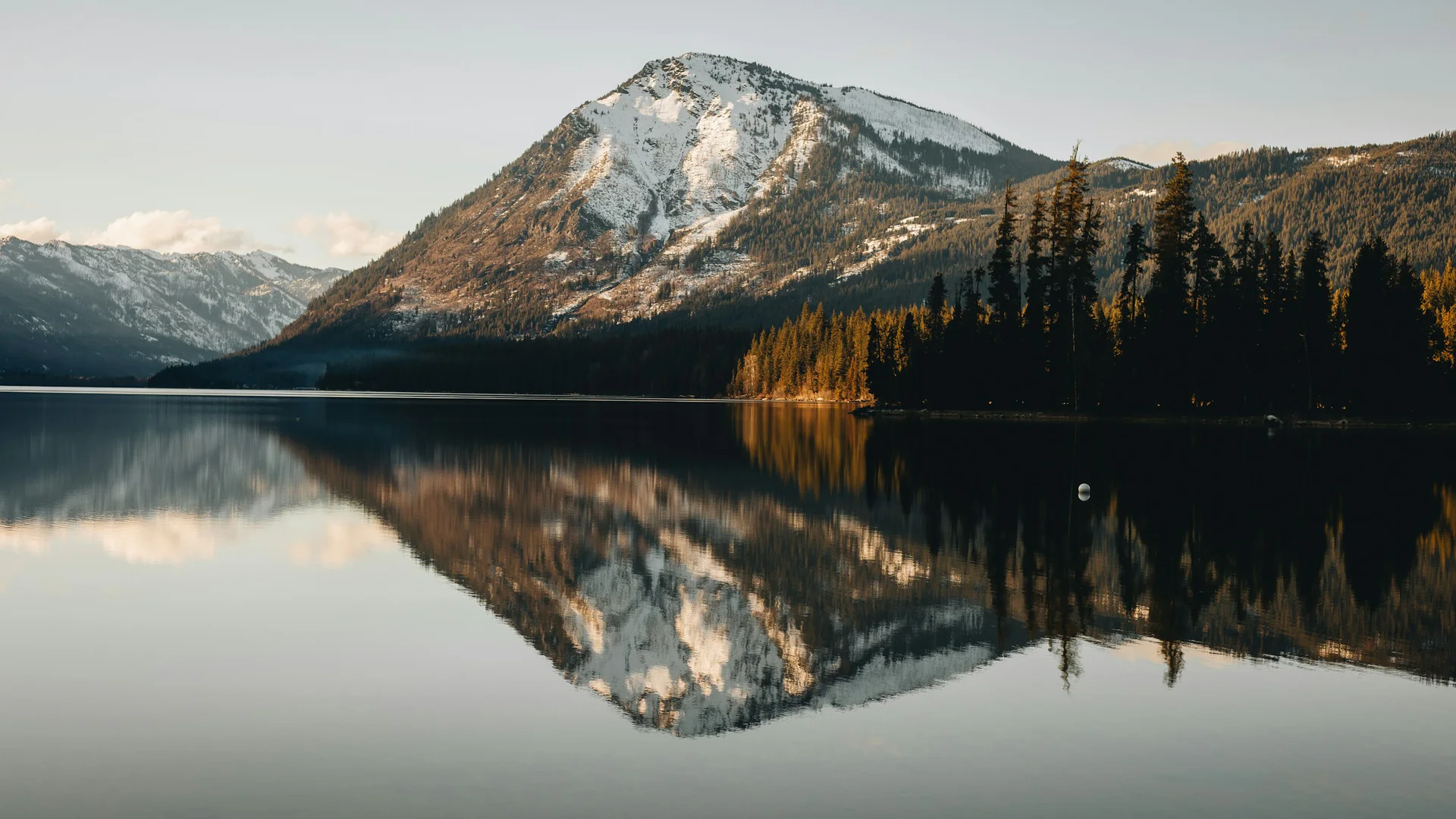 Verschneiter Berg spiegelt sich im ruhigen Lake Wenatchee im warmen Winterlicht