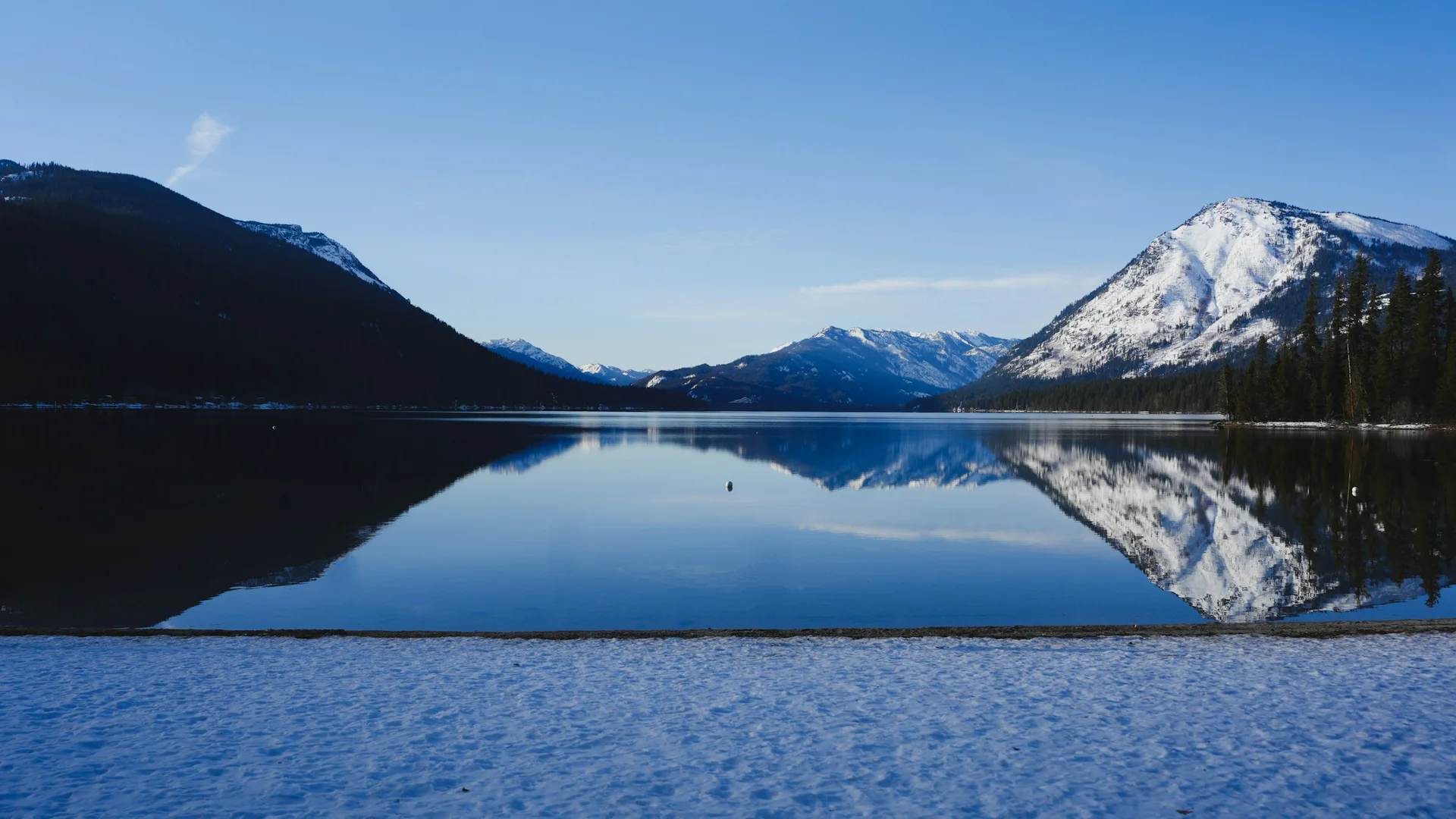 Schneebedeckte Berge und blaues Wasser am winterlichen Lake Wenatchee State Park