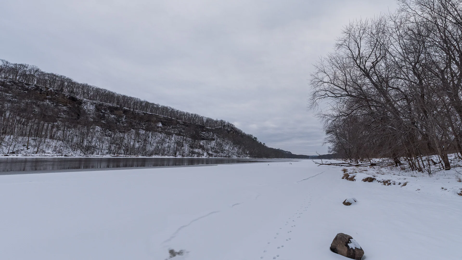 Verschneiter St. Croix River zwischen bewaldeten Hängen im Winter