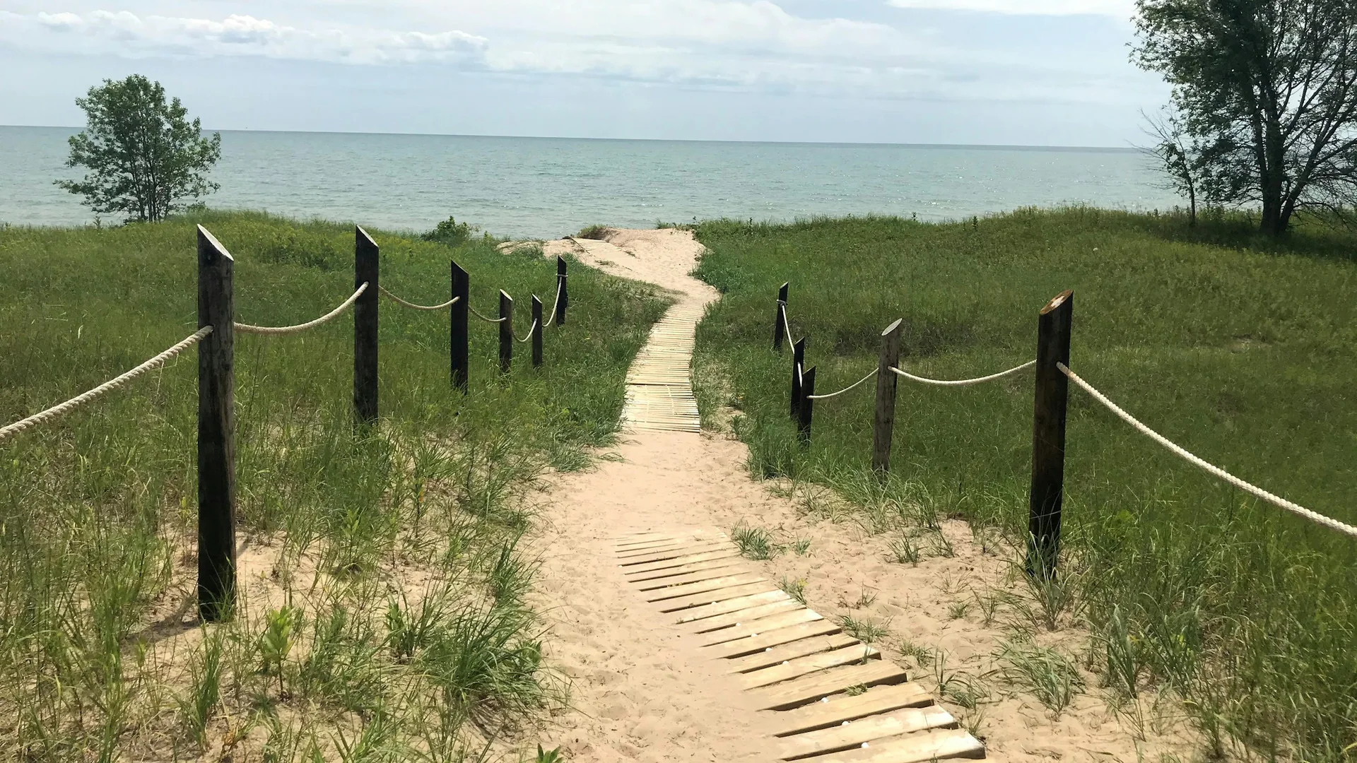 Schmaler Holzweg führt durch Dünen und Strandgras zum Lake Michigan im Kohler-Andrae State Park