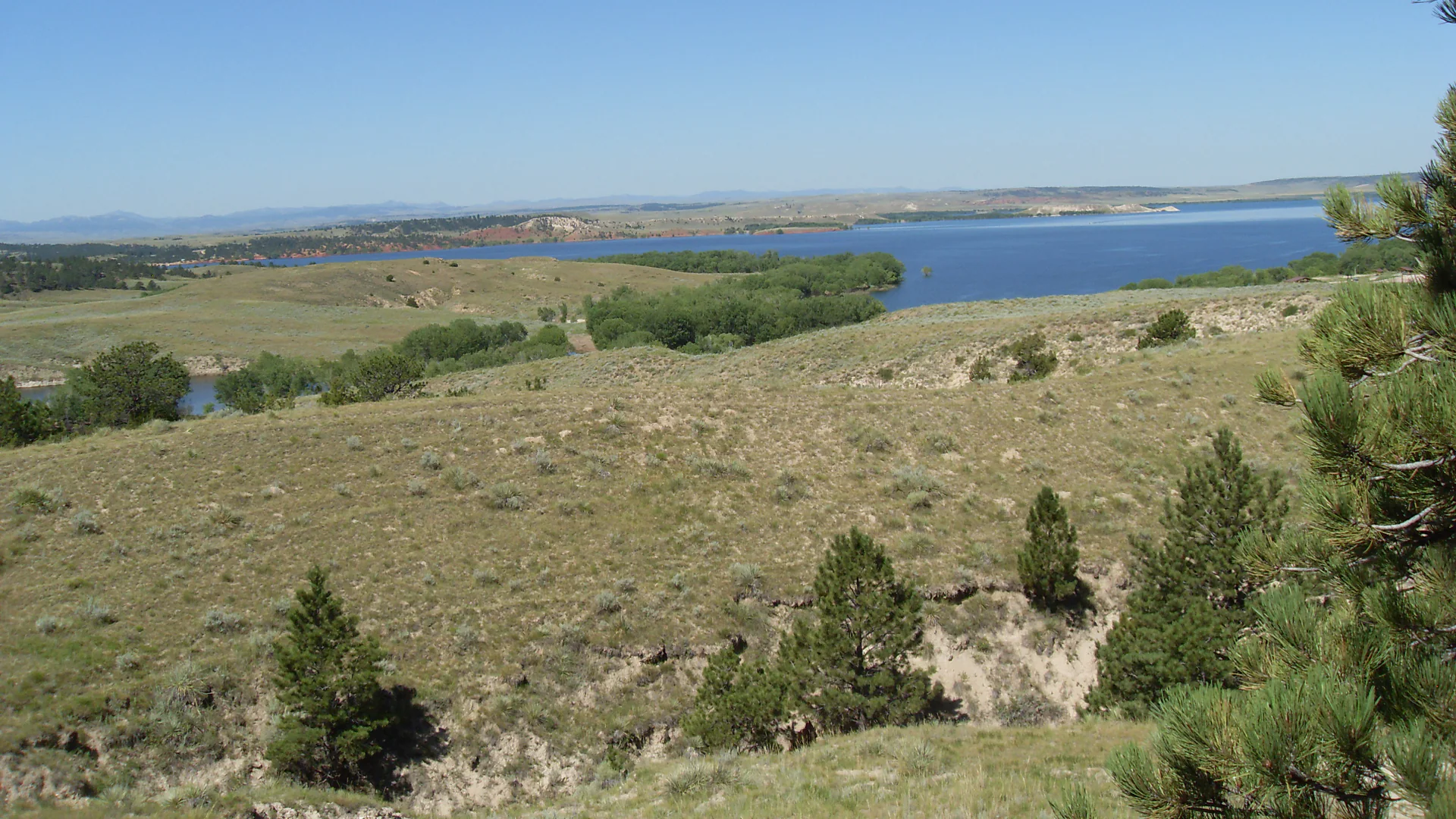 Weiter Blick über trockenes Hügelland zum blauen Glendo Reservoir