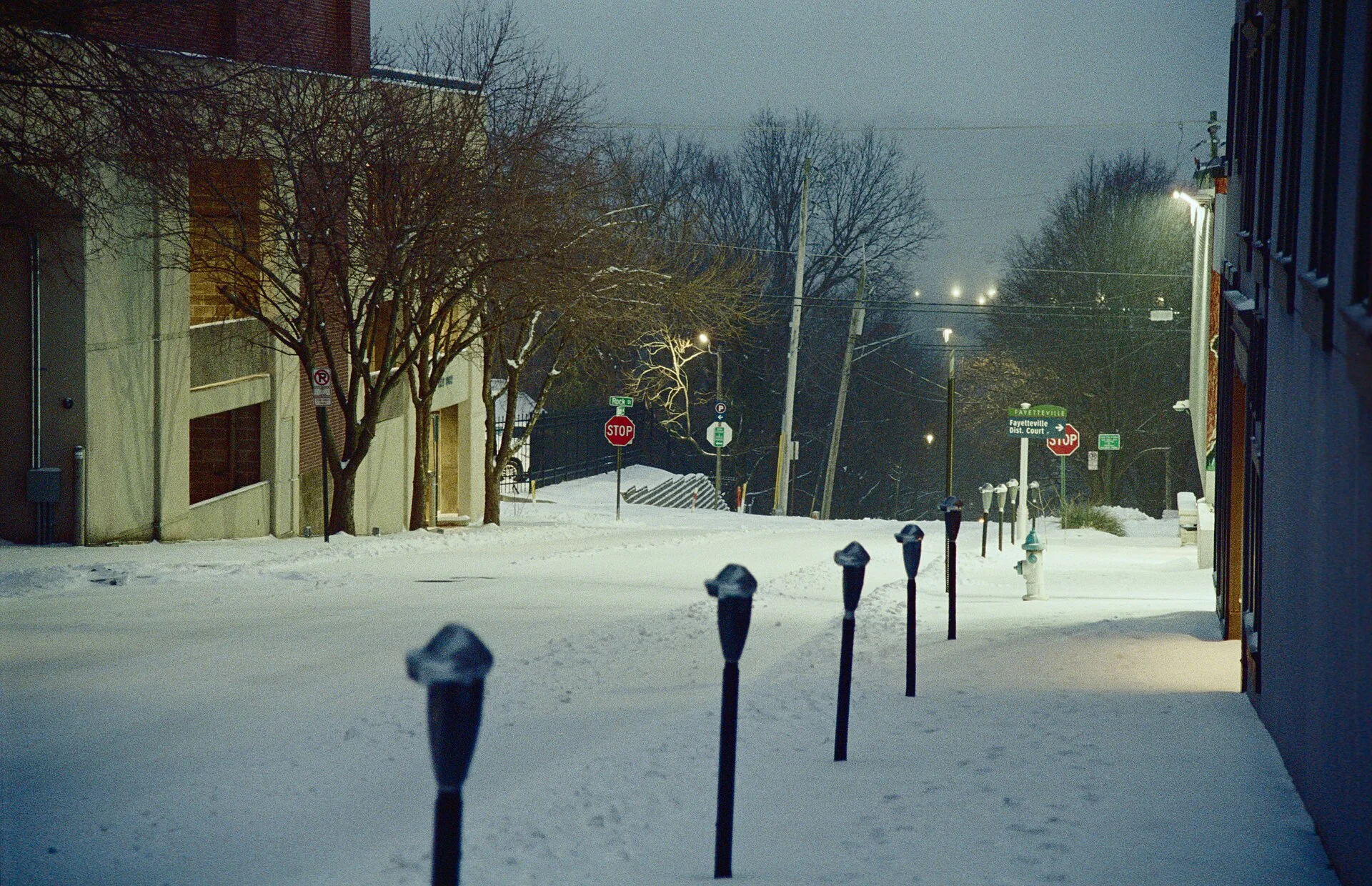 Snowy January evening looking south on Block Ave. in downtown Fayetteville, Arkansas. Taken January 24th, 2026 with a Nikon F100 and Lomo 800 iso film.
