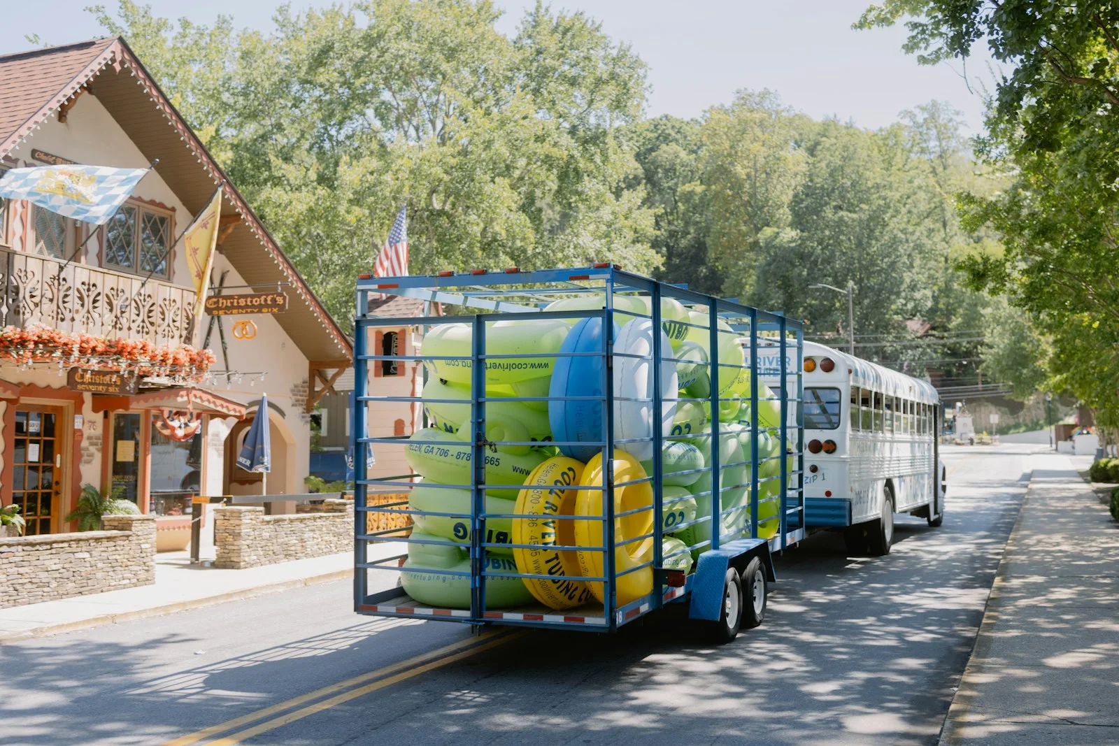 A trailer of tubes is pulled by a bus.