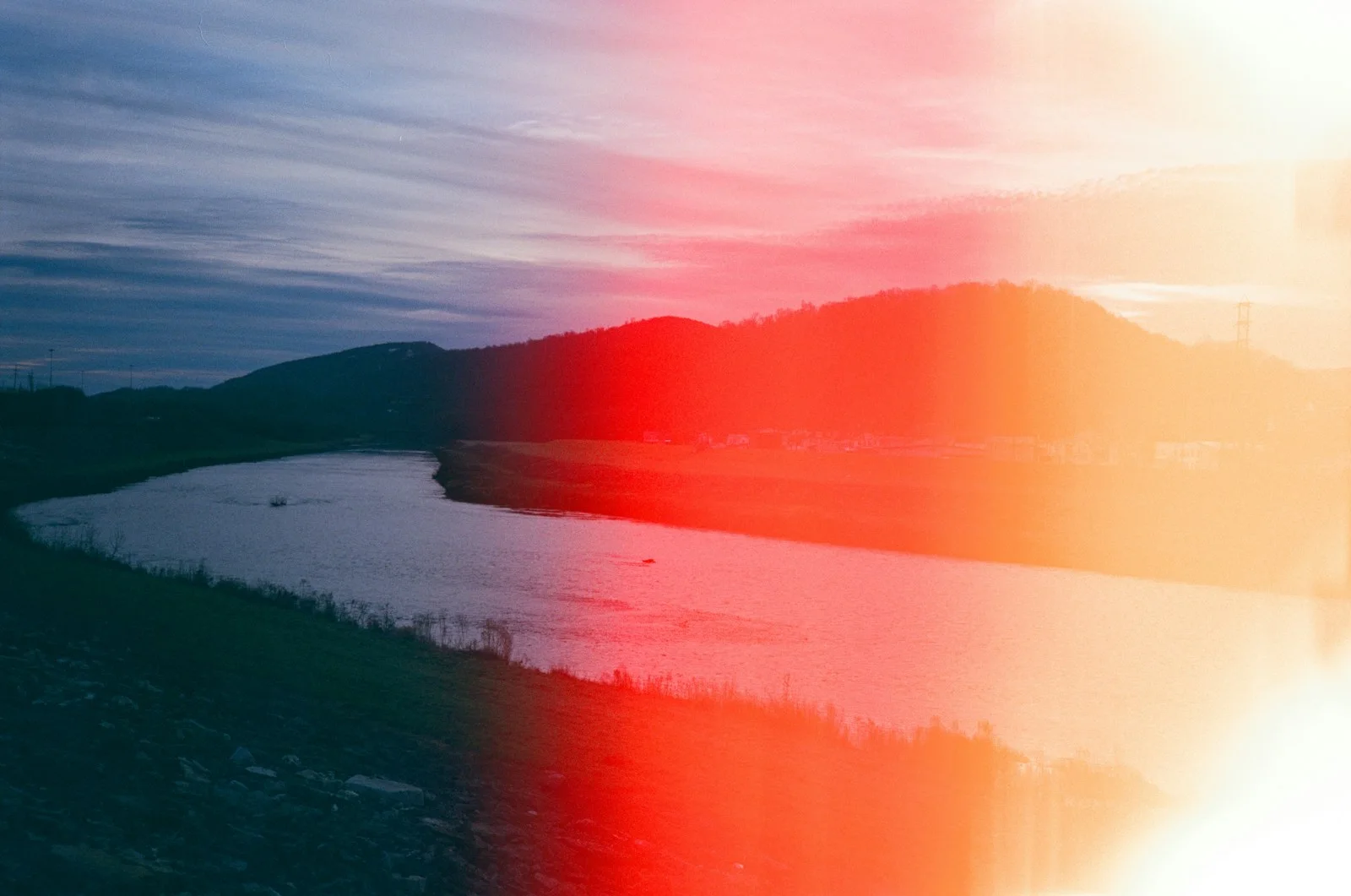 body of water near mountain during sunset