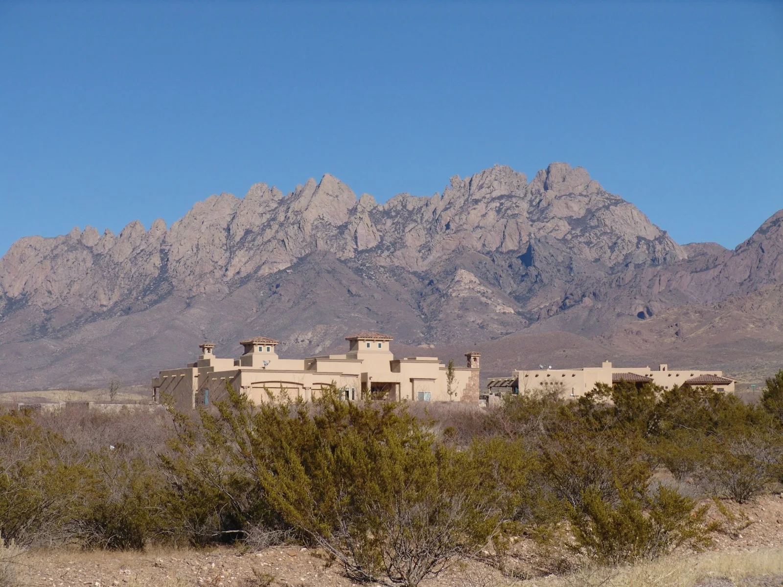 a house in the middle of a desert with mountains in the background