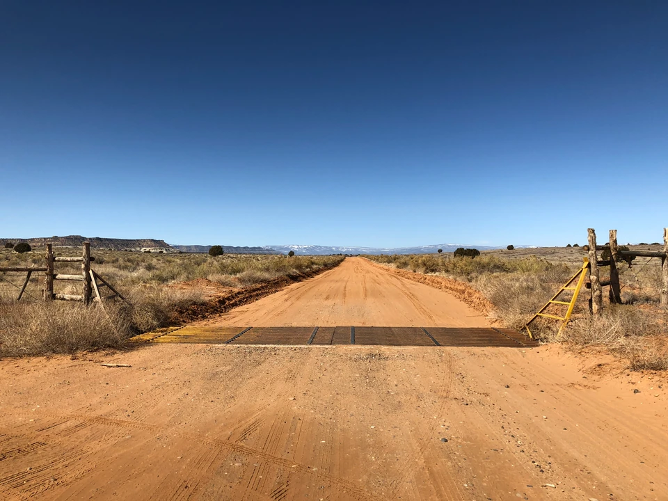 Unbefestigte Straße mit Zaun und weitem Blick bei Escalante
