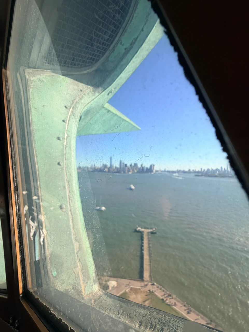Fensterrahmen und Außenhaut der Statue vor Hafen und Manhattan-Skyline