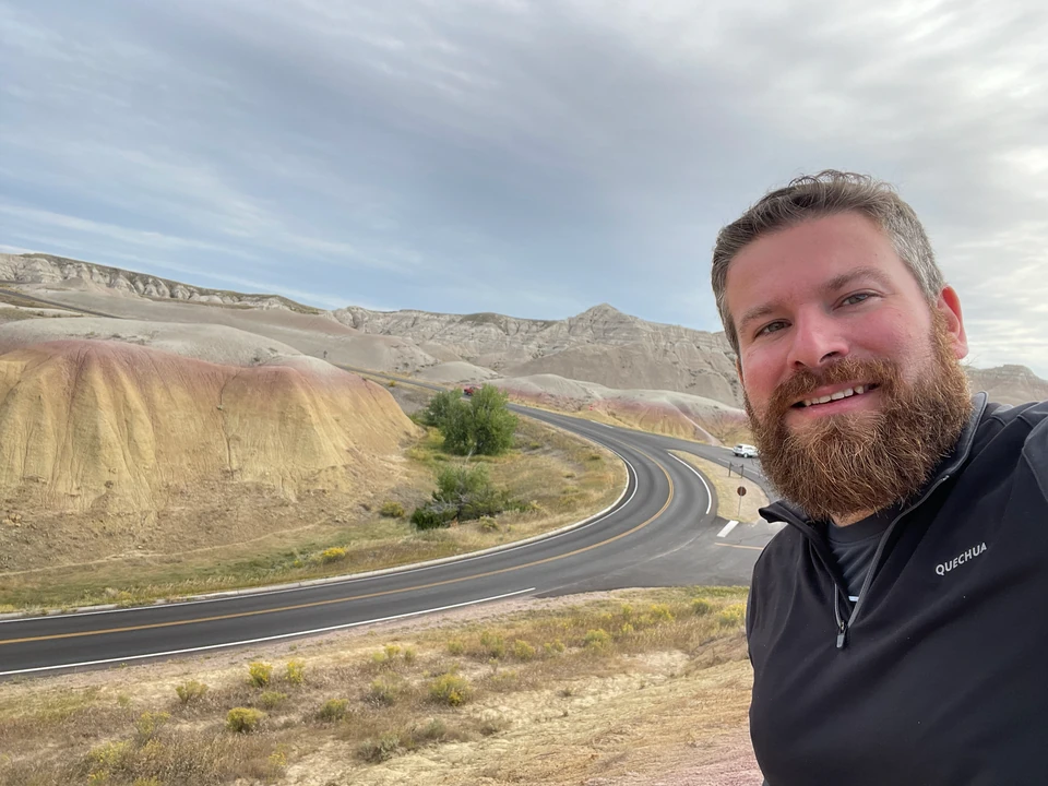 Tobias vor der kurvigen Straße und gelben Schichten in den Badlands