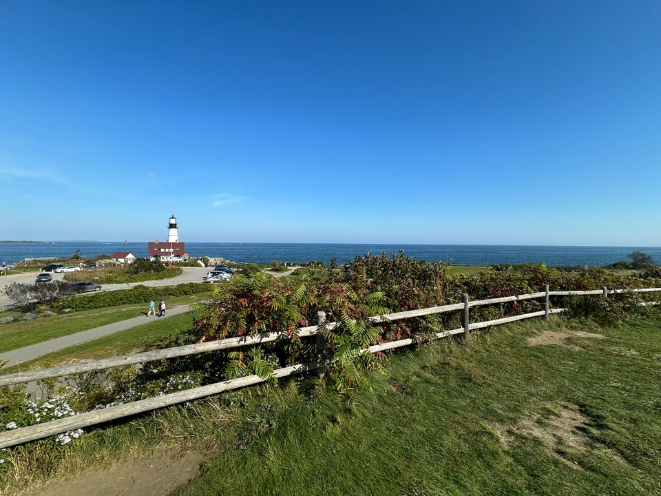 Weg und niedriger Zaun im Fort Williams Park mit Portland Head Light am Meer