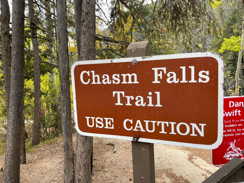 Braunes Wegschild zum Chasm Falls Trail und Warnhinweis am Weg